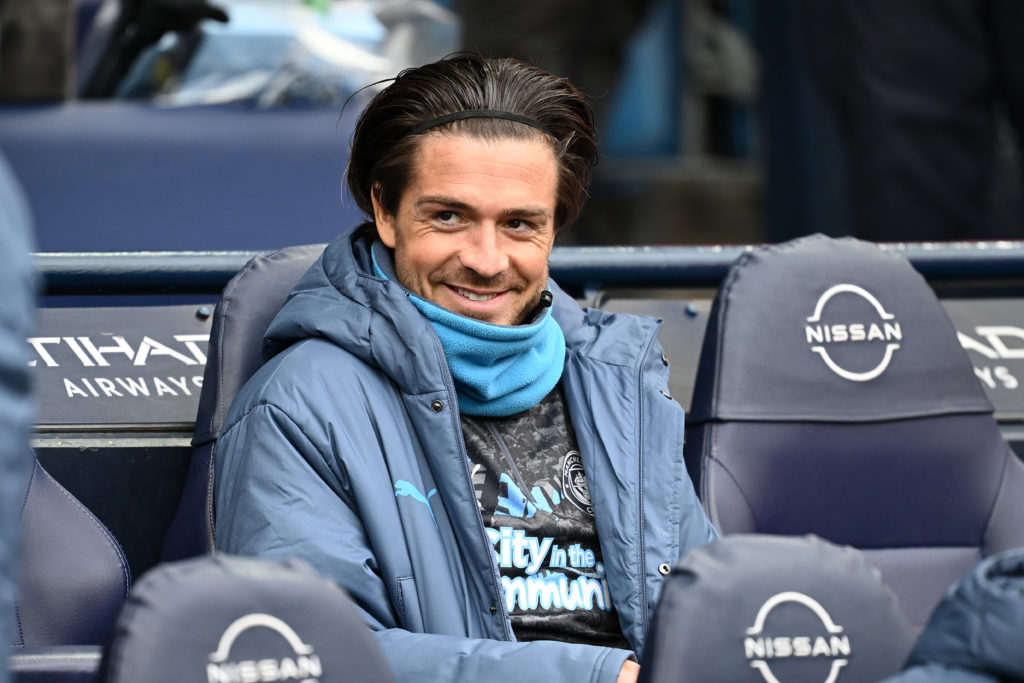 Jack Grealish smiles on the Man City bench.