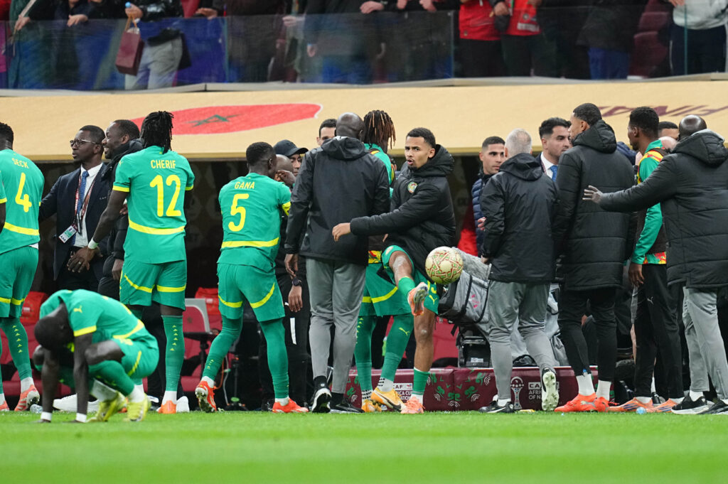 Ilimann Ndiaye kicks a ball amid chaos at the AFCON final.